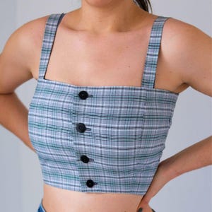 Peut inclure: Un haut court à carreaux gris et blancs avec de fines bretelles noires et un devant boutonné.