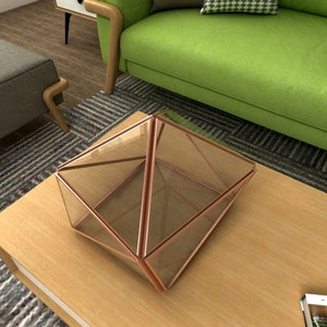 May include: A geometric glass terrarium with a copper frame sits on a wooden table. The terrarium is empty and has a clear glass body.