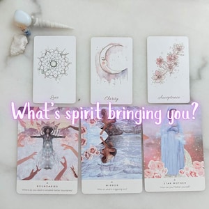 Puede incluir: Un conjunto de cartas de oráculo con ilustraciones de acuarela y texto. Las cartas presentan imágenes de un mandala, una luna creciente y flores. El texto en las cartas incluye las palabras "Amor", "Claridad" y "Aceptación". La frase "What's spirit bringing you?" también es visible.