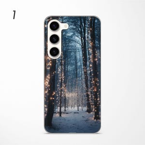 May include: A phone case with a winter forest scene. The trees are covered in twinkling lights and the ground is covered in snow.