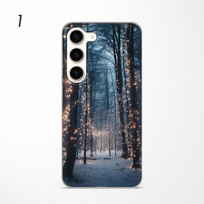 May include: A phone case with a winter forest scene. The trees are covered in twinkling lights and the ground is covered in snow.