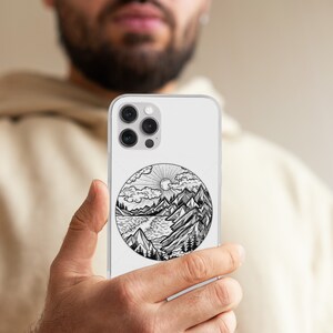 May include: A white phone case with a black and white illustration of a mountain landscape with a lake and sun. The illustration is in a circle.
