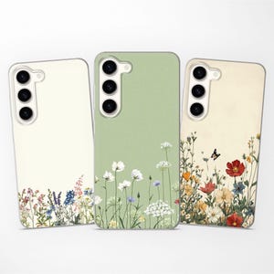 May include: Three phone cases with floral designs. One is light green, one is cream, and one is beige. Each case has a different arrangement of colorful flowers, including red, white, and blue blooms, with a butterfly on one.