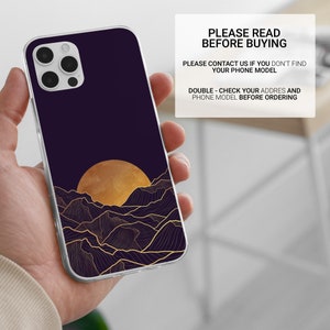 May include: A clear phone case with a design of a golden sun setting behind a mountain range with gold lines on a dark purple background.