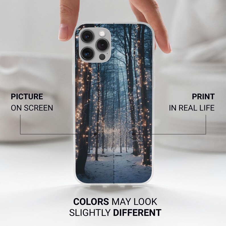 May include: A white phone case with a winter forest scene. The image shows a snowy path lined with trees decorated with twinkling lights.