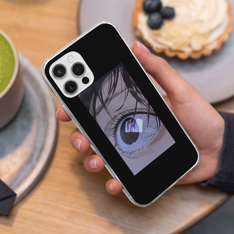 May include: A clear phone case with a black background and a close-up image of an anime eye with red veins. The eye is looking directly at the viewer.