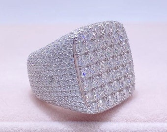 May include: A silver ring with a square-shaped top set with small, clear stones.