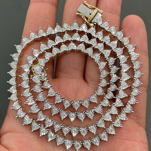May include: A gold chain necklace with a heart-shaped diamond pattern. The necklace is made of white gold and features a clasp closure.