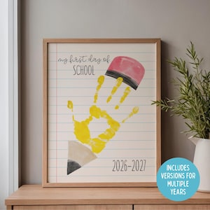 Può includere: Stampa incorniciata con un design a impronta di mano, con un'impronta di mano gialla che forma una matita con una gomma rosa. Il testo "my first day of SCHOOL" e gli anni "2026-2027" sono visualizzati. Include versioni per più anni.