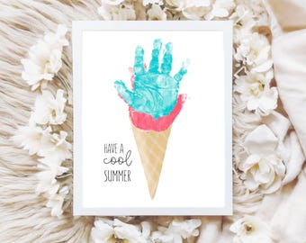 May include: A framed print featuring a handprint design resembling an ice cream cone. The handprint is in shades of blue and pink, with a cone below. The text "Have a cool summer" is printed below the cone.