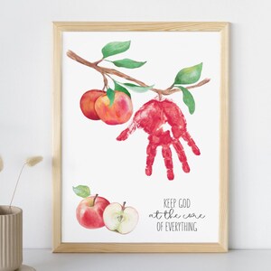 May include: Watercolor print in a wooden frame featuring red apples and a handprint. The artwork includes a branch with green leaves and the text "KEEP GOD at the core OF EVERYTHING".