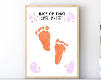 May include: A framed Halloween-themed print with orange footprints and the text "Trick or Treat Smell My Feet." The print includes purple ghost and star graphics, set against a white background.