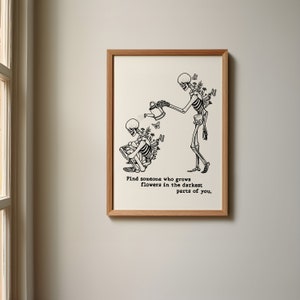 Könnte beinhalten: Schwarz-weiß-Illustration von zwei Skeletten. Ein Skelett gießt Blumen, die aus dem Rücken des anderen Skeletts wachsen. Der Text lautet "Finde jemanden, der Blumen in den dunkelsten Teilen von dir wachsen lässt."