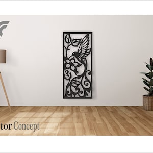 以下が含まれることがあります： 花柄のアクセントが施された、飛行中のハチドリをモチーフにした黒い金属製の壁飾り。デザインは長方形のフレームで囲まれています。