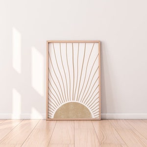 Peut inclure: Une impression encadrée avec un design minimaliste d'un soleil avec des rayons de couleur brun clair sur un fond blanc.