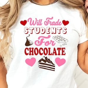 May include: White t-shirt with the text "Will Trade Students For Chocolate" in pink and red. The design includes heart shapes, a chocolate kiss, a chocolate bar, and a slice of cake.