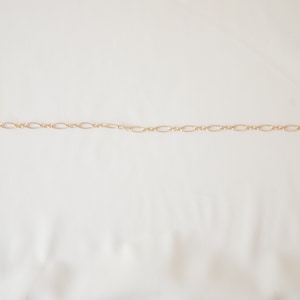 May include: A gold chain necklace with a delicate, oval-shaped link design.