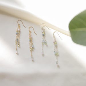 May include: Three pairs of gold dangle earrings with multiple strands of chain and small beads in shades of pink, green, and blue.