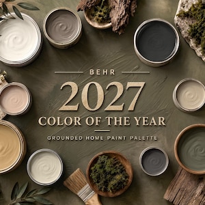 May include: A collection of round paint containers in various shades including white, beige, grey, and green, arranged around the text BEHR 2027 COLOR OF THE YEAR GROUNDED HOME PAINT PALETTE. A wooden brush and natural moss are placed nearby.