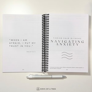 May include: An open spiral bound journal with a white cover and black text. The left page has a quote from Psalm 56:3, "When I am afraid, I put my trust in you." The right page has the title "Finding Calm in Focus: Navigating Anxiety" with a wavy line graphic.
