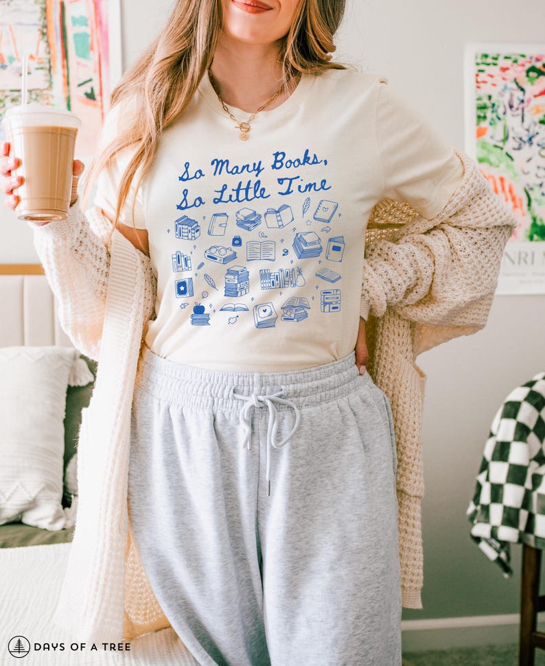 May include: A white t-shirt with a blue graphic of books and the text "So Many Books, So Little Time".