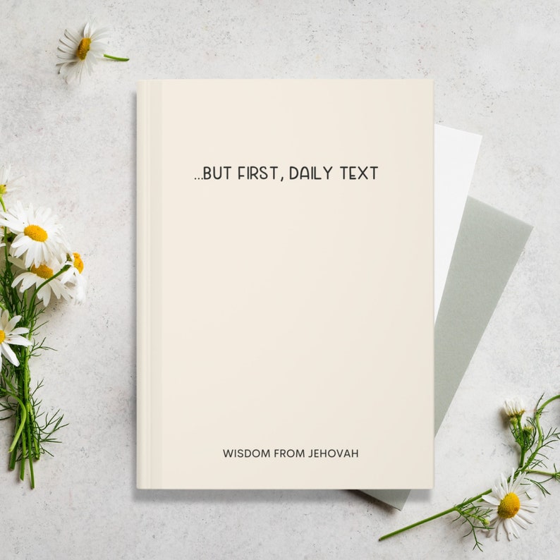 Minimalist beige JW daily text journal with the phrase “…BUT FIRST, DAILY TEXT” in bold black font and “WISDOM FROM JEHOVAH” at the bottom, styled with daisies and neutral stationery on a light stone background.