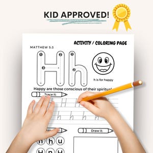 May include: A white activity and coloring page with the text "KID APPROVED!" and "ACTIVITY / COLORING PAGE". The page features the letter "H" with tracing and drawing sections, and the phrase "h is for happy". A child's hand is holding a yellow pencil.