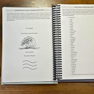 May include: A page from a self-help journal with the title "Understanding Anxiety: Navigating With Hope". The page features a simple illustration of a wave and the text "Stop trying to calm the storm. Calm yourself. The storm will pass."