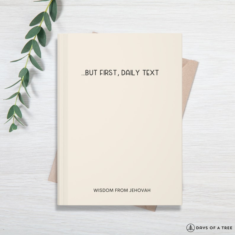 May include: A cream-colored journal with the text "...BUT FIRST, DAILY TEXT" and "WISDOM FROM JEHOVAH" printed on the front cover.