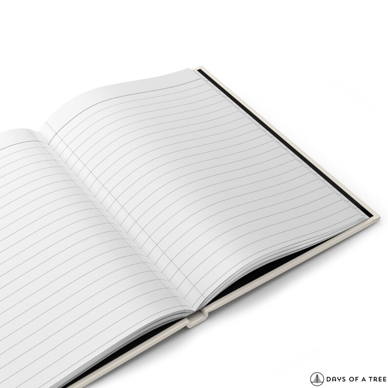 May include: An open lined notebook with a black spine and cream colored cover. The notebook is lying open on a white surface.