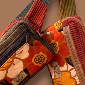Peut inclure: Deux sacs banane en velours côtelé avec des motifs floraux et des fermetures éclair. L'un présente un motif floral rouge et orange, l'autre un motif à rayures vertes et marron. Les deux ont des sangles réglables.
