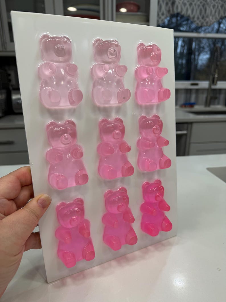 Pu&ograve; includere: Un vassoio bianco contiene nove caramelle gommose a forma di orsetto, in varie tonalit&agrave; di rosa. Gli orsetti gommosi sono disposti in tre file da tre, con l'intensit&agrave; del colore che aumenta dall'alto verso il basso. Gli orsetti sono traslucidi.