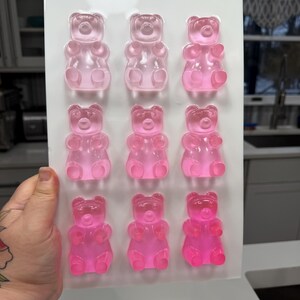 Pu&ograve; includere: Un vassoio di nove orsetti gommosi rosa. Gli orsetti gommosi sono disposti in tre file da tre, con diverse sfumature di rosa. Le caramelle sono traslucide e sembrano appena fatte.