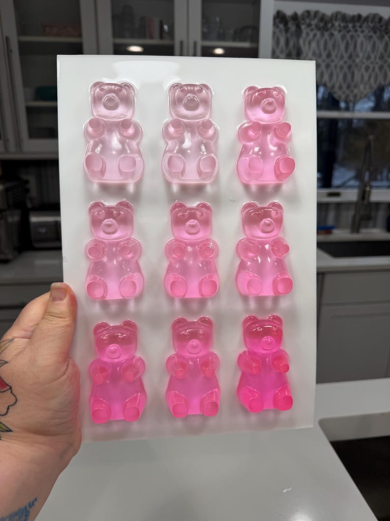 Pu&ograve; includere: Un vassoio di nove orsetti gommosi rosa. Gli orsetti gommosi sono disposti in tre file da tre, con diverse sfumature di rosa. Le caramelle sono traslucide e sembrano appena fatte.