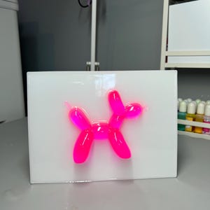 May include: A pink balloon animal shaped like a dog on a white background.