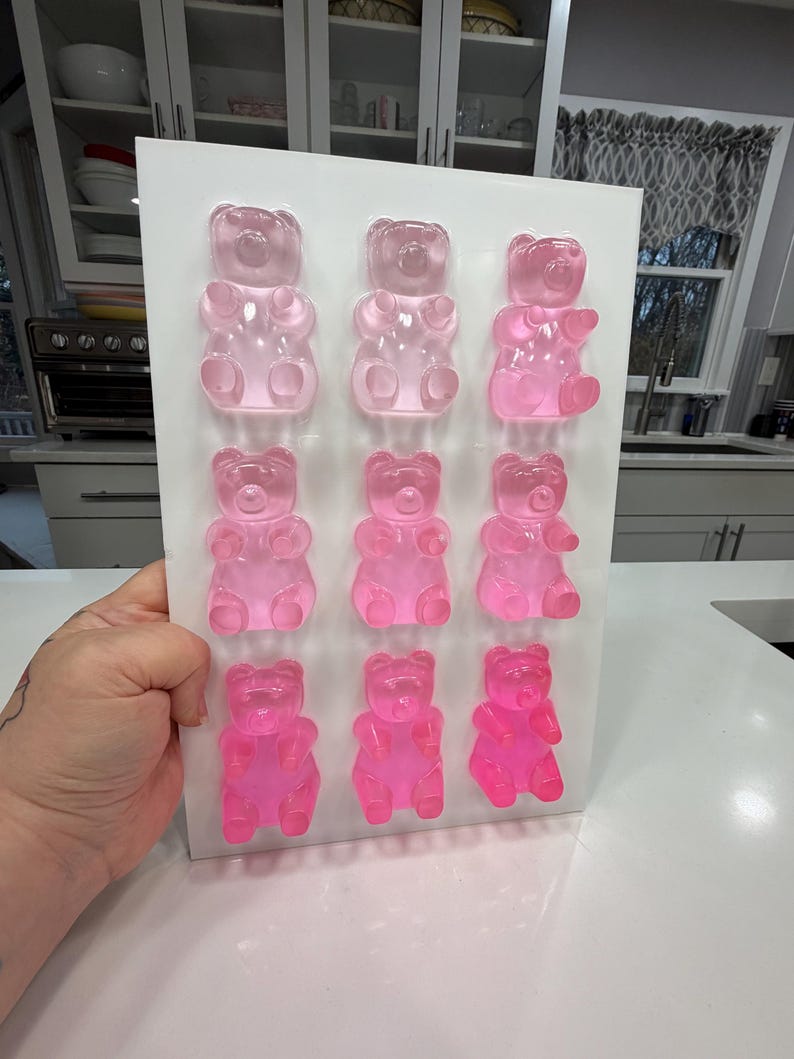 Pu&ograve; includere: Un vassoio rettangolare bianco che contiene dodici caramelle gommose a forma di orsetto rosa. Gli orsetti gommosi sono disposti in tre file da quattro, con diverse tonalit&agrave; di rosa. Lo sfondo mostra una cucina con mobili bianchi e un piano di lavoro.