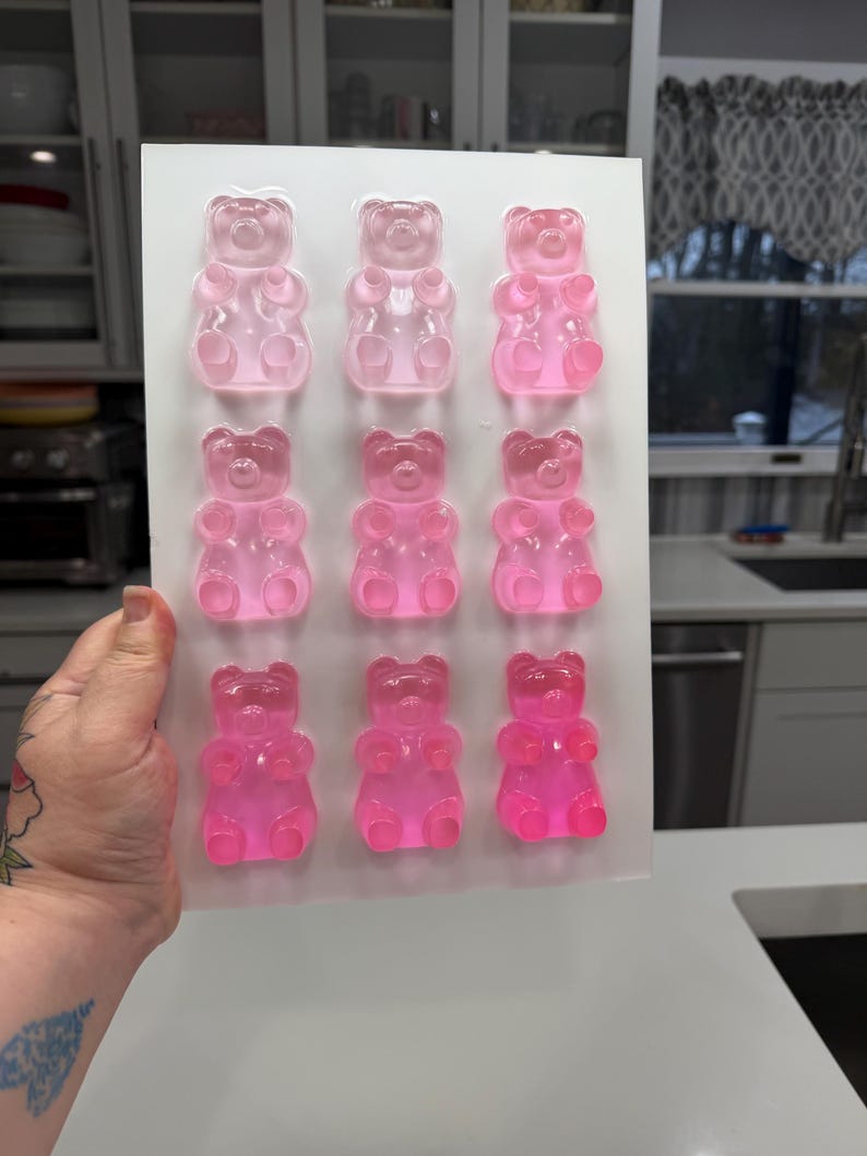 Pu&ograve; includere: Uno stampo rettangolare bianco riempito con dodici caramelle gommose a forma di orsetto in varie tonalit&agrave; di rosa. Gli orsetti gommosi sono disposti in tre file da quattro. Le caramelle sono traslucide e sembrano essere fatte di gelatina.