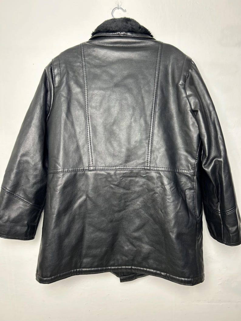 May include: Black leather jacket with a faux fur collar. The jacket has a double breasted closure and a long sleeve design.