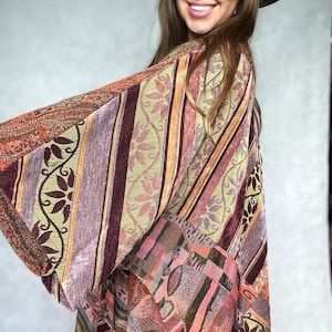May include: A long, multi-colored, striped and patterned kimono with a burgundy, pink, and green color scheme. The kimono is made of a soft, woven fabric.