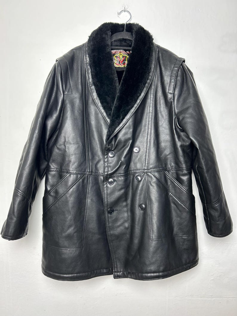 May include: A black leather coat with a faux fur collar. The coat has a double breasted closure and a long length.