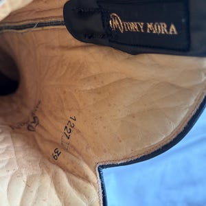 Puede incluir: Vista interior de una bota de cuero negro con una plantilla beige. La bota presenta el nombre de la marca "TONY MORA" en letras doradas. La plantilla muestra los n&uacute;meros "50", "1227" y "39".