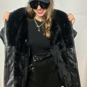 May include: A black faux fur lined leather jacket with a black mini skirt and a black baseball cap with a white "NY" logo.