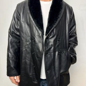 May include: A black leather coat with a large, black fur collar. The coat has a double-breasted closure and a long, straight silhouette.