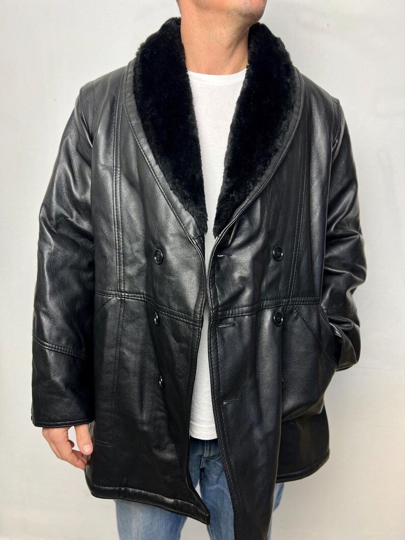 May include: A black leather coat with a large, black fur collar. The coat has a double-breasted closure and a long, straight silhouette.