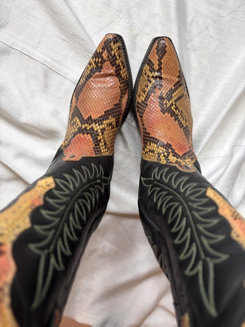 Puede incluir: Botas de vaquero con estampado de piel de serpiente en la punta y la ca&ntilde;a. Las botas tienen una base de cuero negro con costuras decorativas en color verde claro.