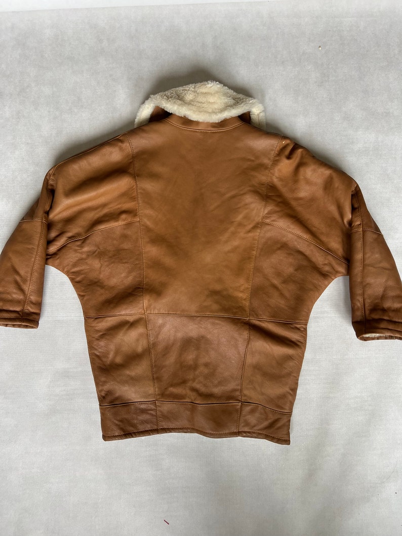 May include: A brown leather jacket with a white faux fur collar. The jacket has a long, loose fit and is made of a soft, supple leather.