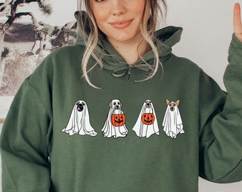 May include: A green hooded sweatshirt featuring a design of four dogs dressed as ghosts for Halloween. The dogs are wearing white sheets with eye holes and one dog is holding a pumpkin bucket.
