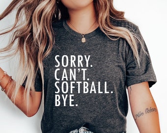 May include: A dark gray t-shirt with the text "SORRY. CAN'T. SOFTBALL. BYE." printed in white.