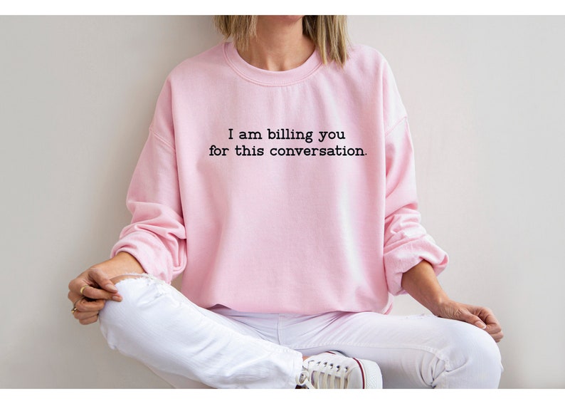 May include: A pink sweatshirt with the text "I am billing you for this conversation." printed on the front.