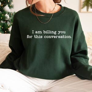 May include: A dark green sweatshirt with the text "I am billing you for this conversation." printed in white.